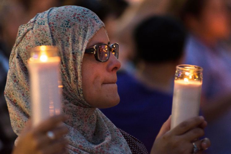 Eine Frau hält eine Kerze für die Opfer des Orlando-Attentats