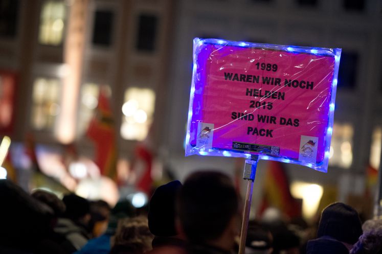 Anhänger der Pegida-Bewegung demonstriert mit einem Schild "1989 waren wir noch Helden 2015 sind wir das Pack" vor der Frauenkirche in Dresden