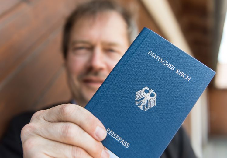 Ein Reichsbrüger hält seinen blauen Reisepass in die Kamera, auf dem steht: Deutsches Reich, Reisepass