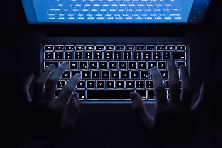 Ein Mann schreibt auf einem erleuchteten Computer-Keyboard.