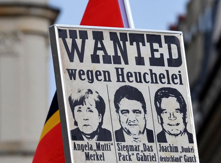 Auf einer Kundgebung des islam- und fremdenfeindlichen Bündnisses Pegida  in Dresden (Sachsen) halten Anhänger ein Schild mit dem Schriftzug "Wanted wegen Heuchelei" über den Porträts von Angela Merkel, Sigmar Gabriel und Joachim Gauck in die Höhe