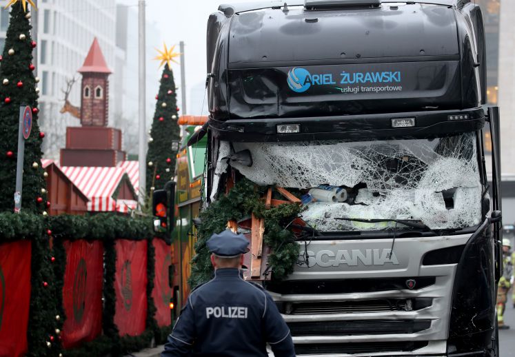 Ein Polizist steht am 20.12.2016 in Berlin vor einem beschädigten LKW. Bei einem möglichen Anschlag war ein Unbekannter am Montag (19.12.) mit einem Lastwagen auf einen Weihnachtsmarkt an der Gedächtniskirche gefahren.