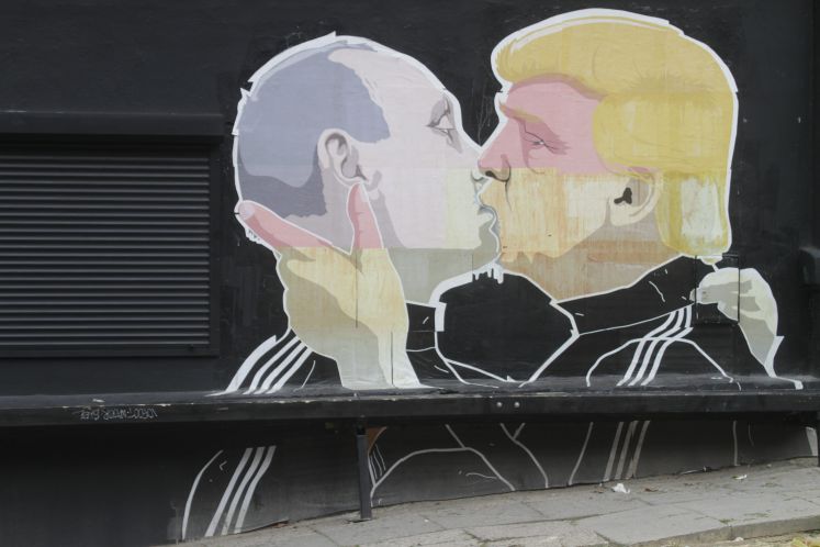 Graffiti auf einer Hausfassade, Trump küsst Putin.