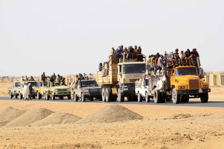 Lastwagen transportieren Flüchtlinge durch eine afrikanische Wüste