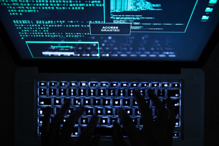 Ein Hacker verwendet ein Programm um mit seinem Laptop eine Seite zu hacken, auf dem Bildschirm ist "Access Granted" zu lesen.