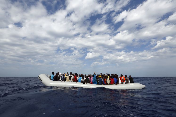 Ein völlig mit afrikanischen Flüchtlingen überladenes Schlauchboot treibt auf dem offenen Meer.
