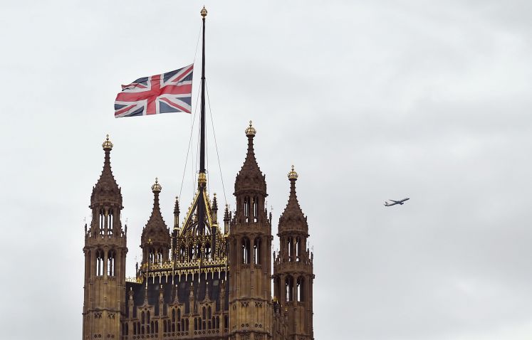 Der Westminster-Palast, Sitz des britischen Parlaments, mit dem Victoria Tower (l) und dem Elizabeth Tower mit Big Ben. Die britische Flagge hängt auf Halbmast.
