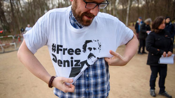 Ein Mann zieht sich ein T-Shirt mit der Aufschrift "# Free Deniz" über