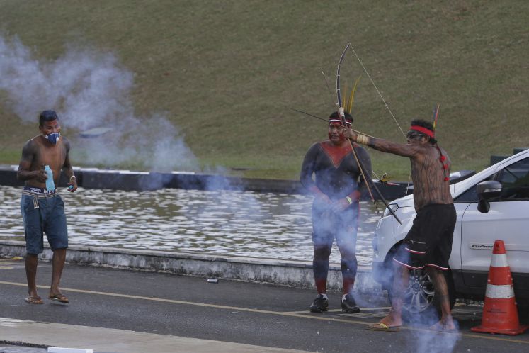 Inmitten von Tränengas, das von der Polizei eingesetzt wurde, spannt ein Indigener seinen Pfeil und Bogen