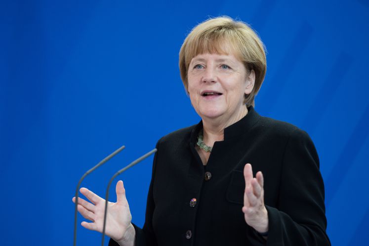 Angela Merkel spricht auf einer Konferenz mit ausladenden Handbewegungen nach links und rechts