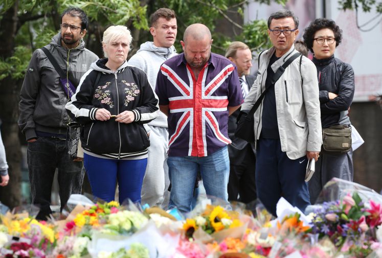 Eine Gruppe Menschen betrachtet die Kondolenzblumen nach mehreren islamistischen Attacken in London
