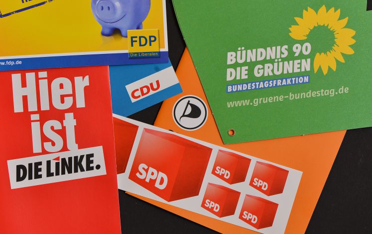 Pogramme von deutschen politischen Parteien liegen zusammen auf einem Tisch.
