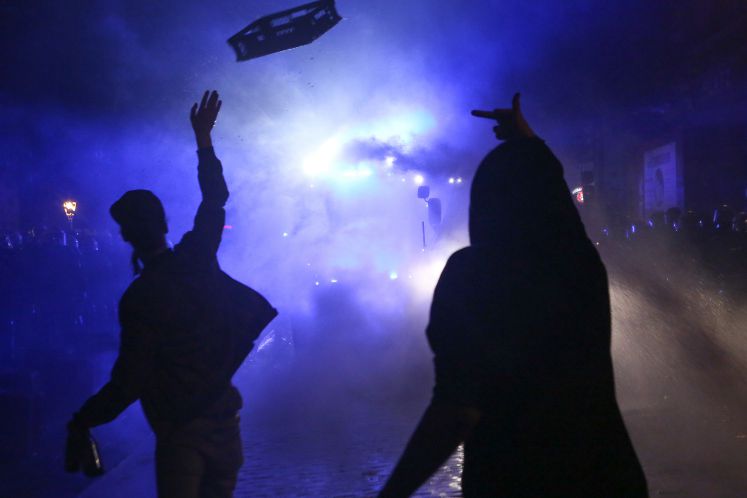 Am Rande des G20 Gipfels werden Demonstranten mit Wasserwerfern beschossen. Sie strecken ihnen den Mittelfinger entgegen und werfen einen Korb.