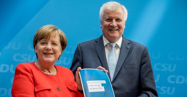 Angela Merkel und Horst Seehofer halten das neue Unions-Programm in den Händen