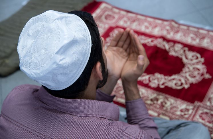 Ein Muslim kniet auf seinen Gebetsteppich und betet