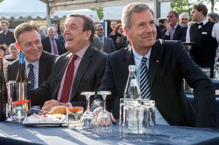 Alt-Bundeskanzler Gerhard Schröder (SPD, M) sitzt am 30.06.2014 zu Beginn der Sommerfestes in der Landesvertretung von Niedersachsen in Berlin neben Alt-Bundespräsident Christian Wulff (CDU). Links sitzt der Vorsitzende der SPD-Bundestagsfraktion, Thomas Oppermann.