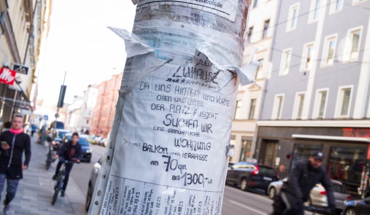 Ein vergilbter Zettel klebt an einem Laternenpfahl in München. Eine Wohnung wird gesucht, die 70 Quadratmeter groß sein soll und nicht teurer als 1300 Euro.