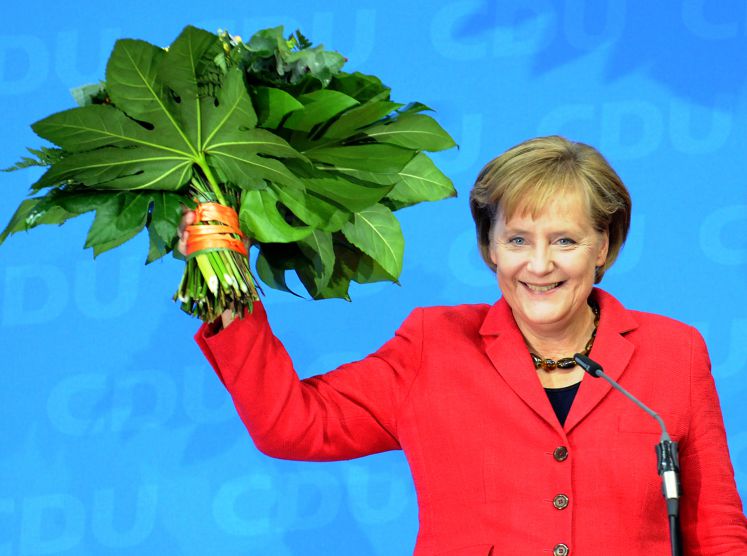 Angela Merkel jubelt mit einem Blumenstrauß in der Hand