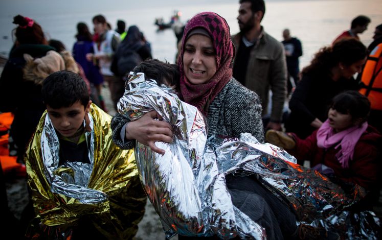 Eine Mutter trägt am 09.03.2016 ihr Kind nach der Ankunft mit einem Schlauchboot aus der Türkei auf der griechischen Insel Lesbos in der Nähe der Hafenstadt Mitilini (Mytilini) an den Strand.