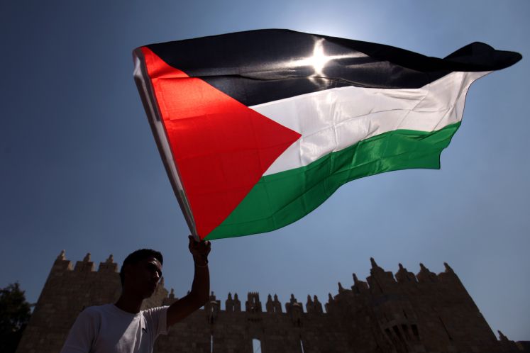 Ein Mann hält die palästinensische Flagge in den Wind