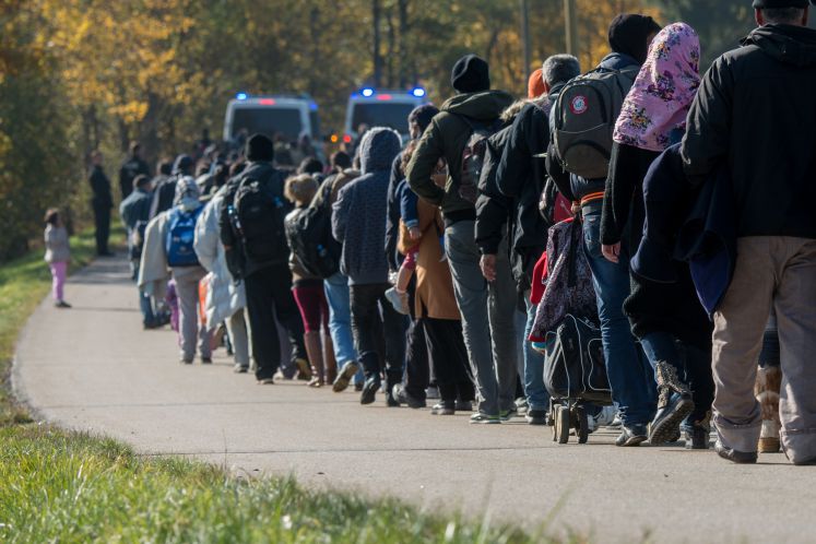 Flüchtlinge gehen am 27.10.2015 nahe Wegscheid (Bayern) hinter Fahrzeugen der Bundespolizei