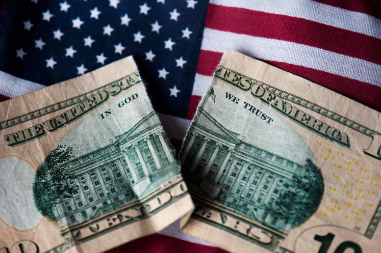 Eine zerrissene Dollarnote liegt auf einer USA-Flagge
