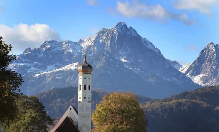 In herbstlicher Landschaft vor schneebedeckten Bergen steht am 17.10.2013 die Wallfahrtskirche Sankt Coloman bei Hohenschwangau (Bayern)