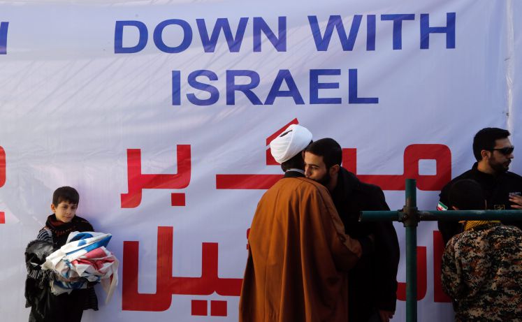 Zwei Iraner umarmen sich vor einem Transparent mit der Aufschrift "Down with Israel"
