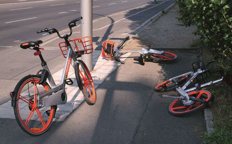 Bikesharing-Fahrräder liegen abgestellt auf einem Gehweg herum