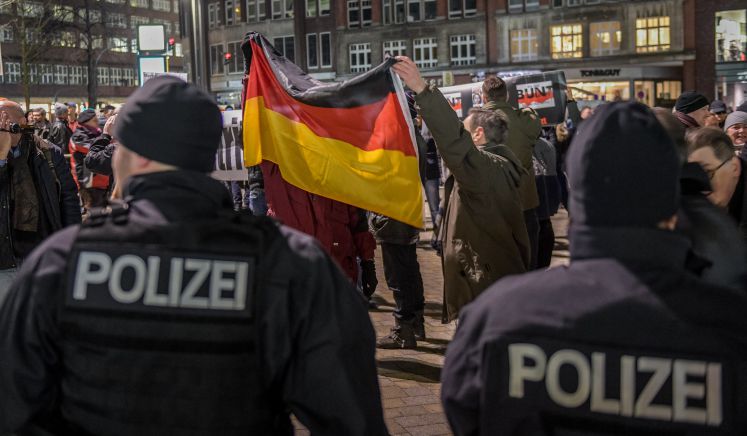 Hamburg: Polizisten sichern eine rechte Demonstration unter dem Motto "Merkel muss weg" auf dem Gänsemarkt, während Demonstranten die deutsche Flagge schwenken.