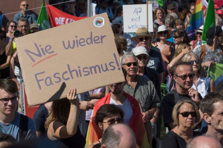 19.08.2018, Hessen, Wiesbaden: Ein Plakat mit der Aufschrift "Nie wieder Faschismus" trägt eine Demonstrantin bei einem Protestzug gegen die "Alternative für Deutschland (AfD)".