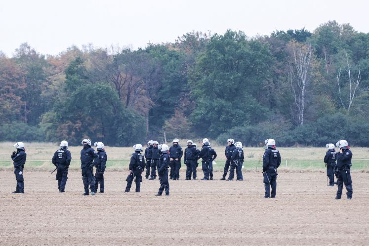 Polizisten stehen auf einem Feld vor dem Hambacher Forst