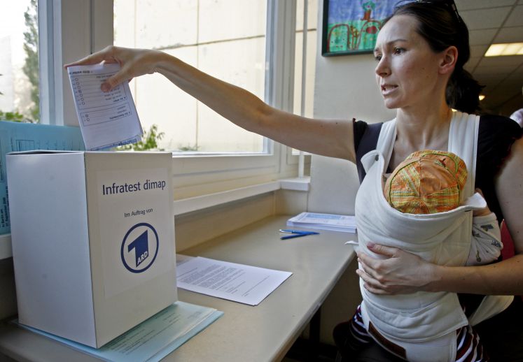 Eine Frau wirft wirft einen Stimmzettel in eine Box für Infratest dimap