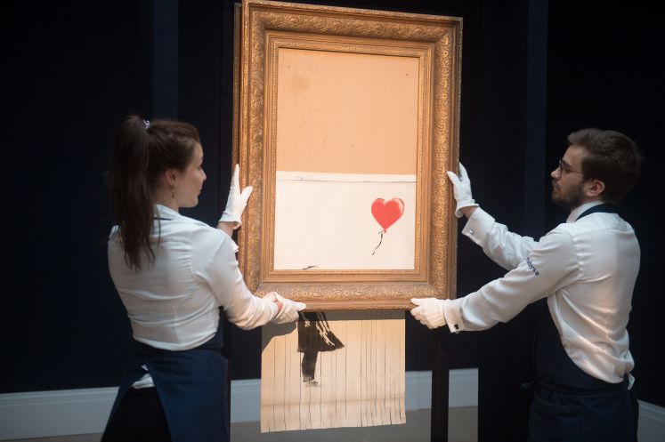 Zwei Mitarbeiter von Sotheby's halten das geschredderte Banksy-Bild