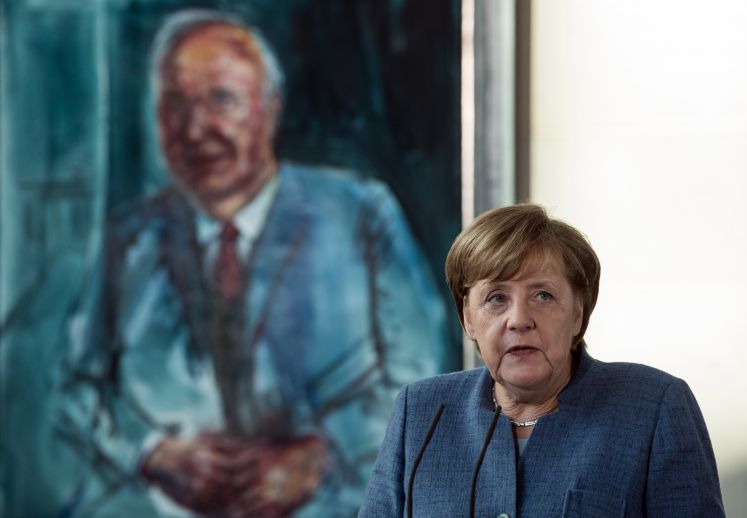 Angela Merkel steht vor einem Gemälde Helmut Kohls