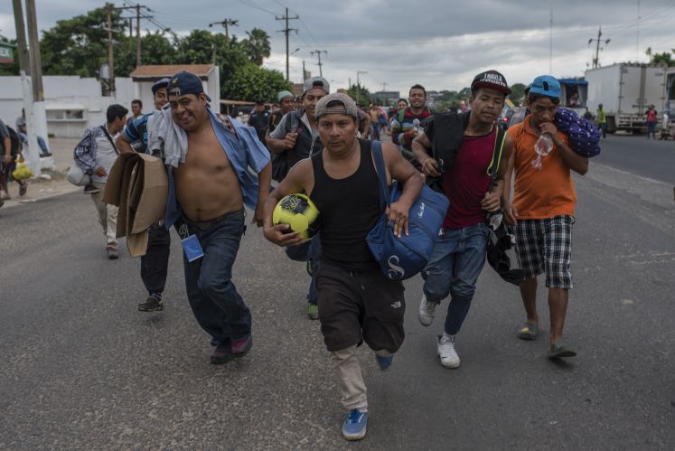 02.11.2018, Mexiko, Sayula de Alemán: Migranten, die soeben einen Ball zur Entspannung bekommen haben, laufen durch die mexikanische Stadt Sayula de Alemán. Derzeit sind Tausende Menschen aus Mittelamerika in mehreren Gruppen auf dem Weg durch Mexiko in Richtung der US-Grenze. US-Präsident Trump hat das Pentagon wegen der Migranten angewiesen, Soldaten an die Grenze zu schicken. 