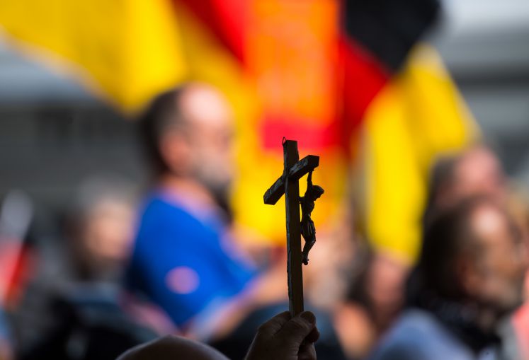 Teilnehmer einer Demo des Frauenbündnisses Kandel halten ein Christus-Kreuz hoch