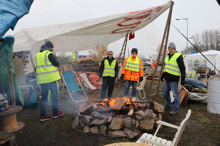  Vier "Gelbwesten" wärmen sich in ihrem Protestcamp nahe Straßburg an einem Lagerfeuer. 