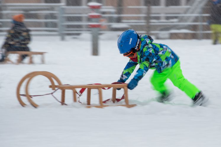 Ein Kind schiebt einen Schlitten im Schnee