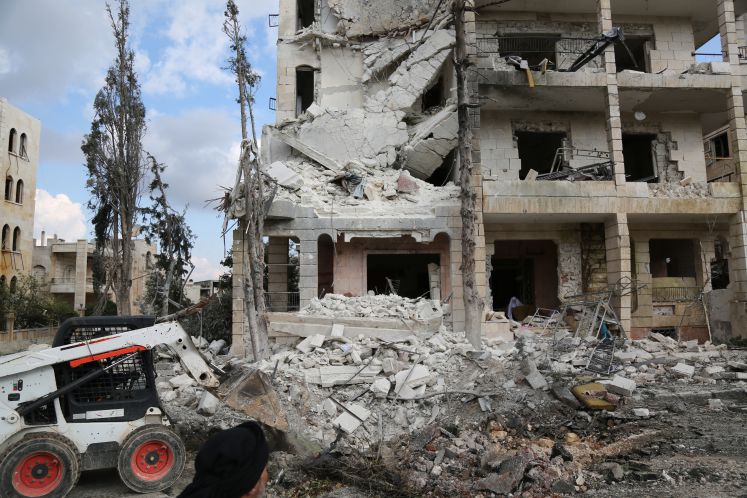 Ein zerstörtes Haus in Syrien. Davor steht ein Bagger.