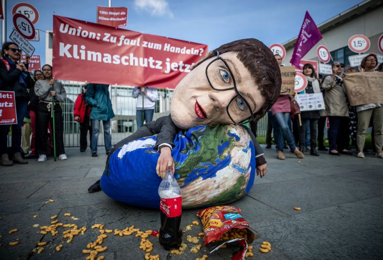 Eine Aktivistin von Campact liegt mit einer Großmaske, die die CDU-Vorsitzende Annegret Kramp-Karrenbauer darstellen soll, bei einer Kundgebung, die mangelnden Klimaschutz der Union bemängelt. Das Klimakabinett trifft sich gleichzeitig im Kanzleramt.