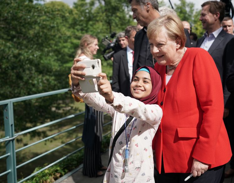 8.08.2019, Berlin: Bundeskanzlerin Angela Merkel (r, CDU) macht während des Tages der offenen Tür der Bundesregierung mit einem jungen Mädchen ein Selfie