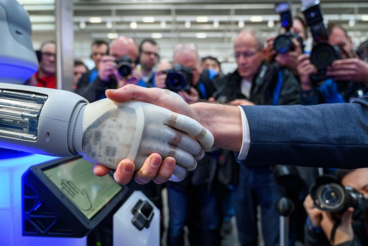 Ein Mensch und ein Roboter geben sich die Hand