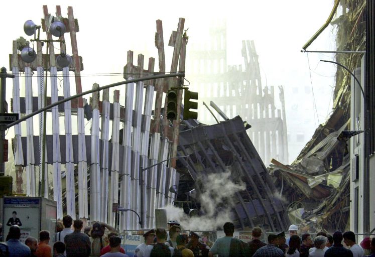 Vor den rauchenden Trümmern des World Trade Center in Manhattan stehen am 19.09.2001 Passanten. Mehr als eine Woche nach dem der verheerende Anschlag konnten sich Passanten erstmalig bis auf wenige hundert Meter der Unglücksstelle nähern. Die Bergung von Leichen oder Leichenteilen aus den Trümmern des World Trade Centers könnte noch mehr als sechs Monate andauern. Das sagten beteiligte Fachleute am 19.9. Reportern in New York. Unter den Trümmern werden mehr als 5500 Tote vermutet. Von den geborgenen Toten k