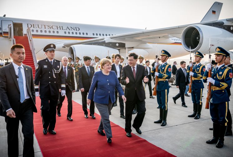 Bundeskanzlerin Angela Merkel steigt nach der Landung am Flughafen Peking in den Airbus A340 ein und wird von Qin Gang begrüßt