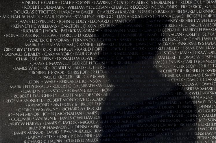 Man sieht den Schatten eines Soldaten auf einem Kriegsdenkmal mit den Namen gefallener US-Soldaten im Vietnamkrieg.