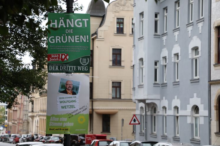 Ein umstrittenes Wahlplakat der Splitterpartei "III Weg" hängt über einem Plakat der grüne