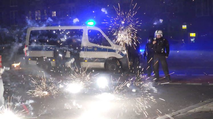 Polizeibeamte stehen hinter explodierendem Feuerwerk an Silvester in Berlin / dpa