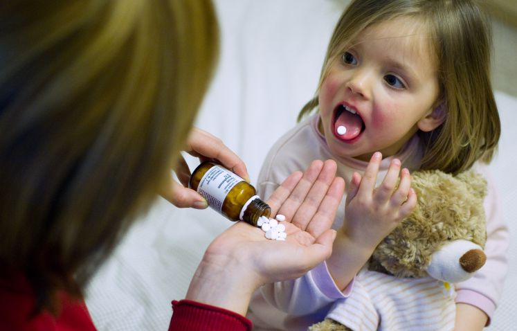 Eine Mutter gibt ihrer erkälteten Tochter das alternativmedizinische Mineralsalz-Präparat "Schüssler Salze".