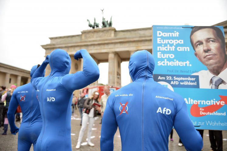 Drei Männer in blauen AfD-Kostümen stehen vor dem Brandenburger Tor